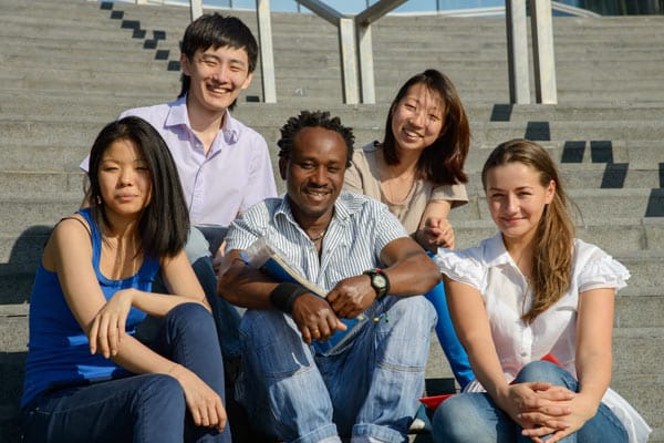 A group of people from different cultures sitting on steps outdoors, at a university, business or social meeting.